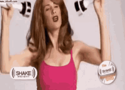 a woman in a pink tank top is holding two dumbbells .