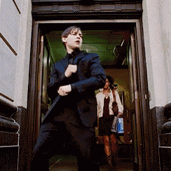 a man in a suit is standing in a doorway with a woman behind him