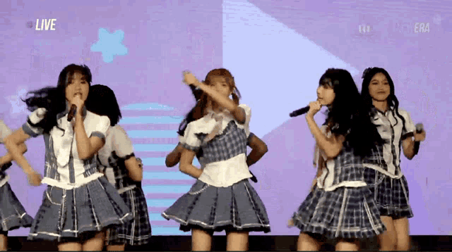 a group of girls are performing in front of a screen that says " live "