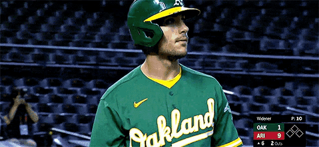 a baseball player for the oakland a's is standing in the dugout