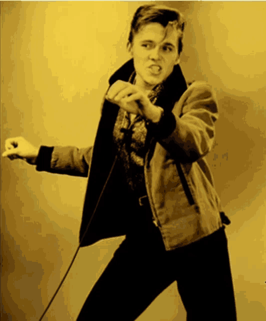 a young man singing into a microphone with a yellow background