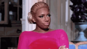 a woman in a pink dress is making a funny face while sitting on a chair .