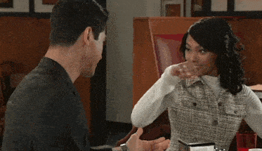 a man and a woman are sitting at a table in a restaurant having a conversation