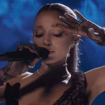 a woman singing into a microphone while wearing a choker