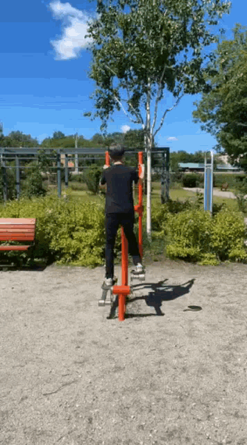 a man in a black shirt is doing exercises on a red machine