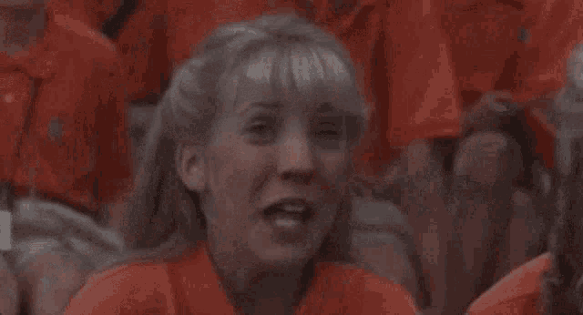 a group of people in red shirts are laughing in a stadium .