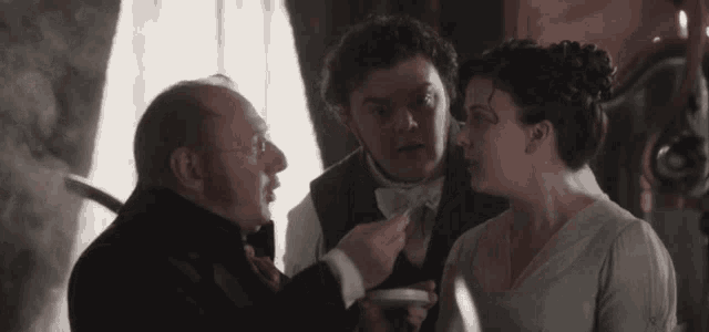 a man is pointing at a woman 's neck while two other men look on