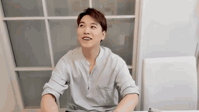 a young man is sitting at a table in front of a window .