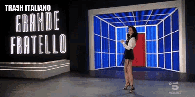 a woman is standing in front of a large sign that says trash italiano grande fratello