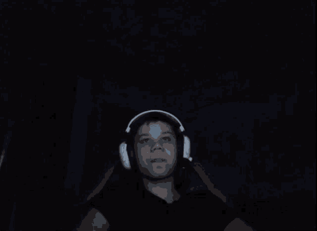 a person wearing headphones in the dark making a funny face