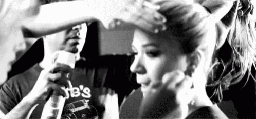 a black and white photo of a woman getting her hair blow dried by a man .