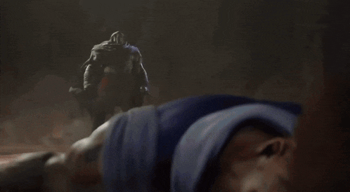 a man is fighting another man in a dark room with a skull in the background .