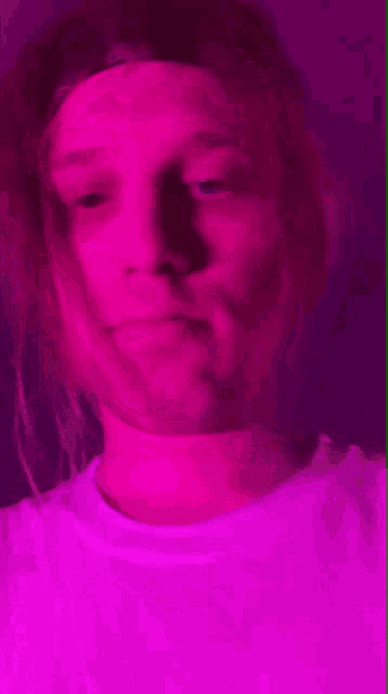 a close up of a person 's face with a pink light behind them