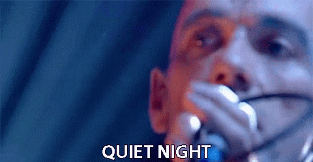a close up of a man singing into a microphone with quiet night written below him