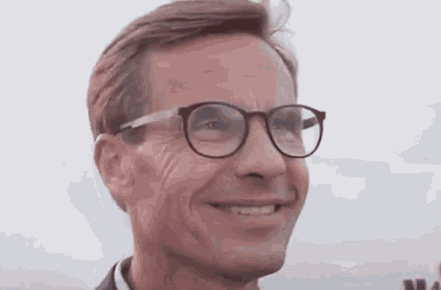 a man wearing glasses is smiling and looking to the side .