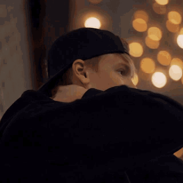 a man wearing a baseball cap and a black hoodie