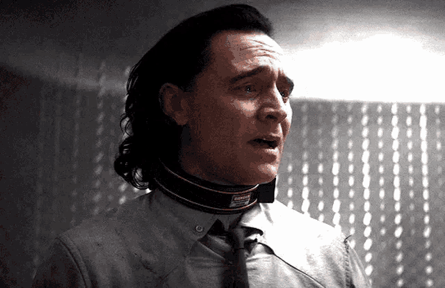a man wearing a collar and tie is standing in a room with his mouth open .