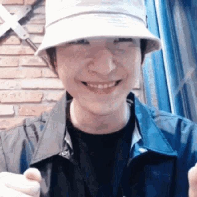 a man wearing a hat and a jacket is smiling .