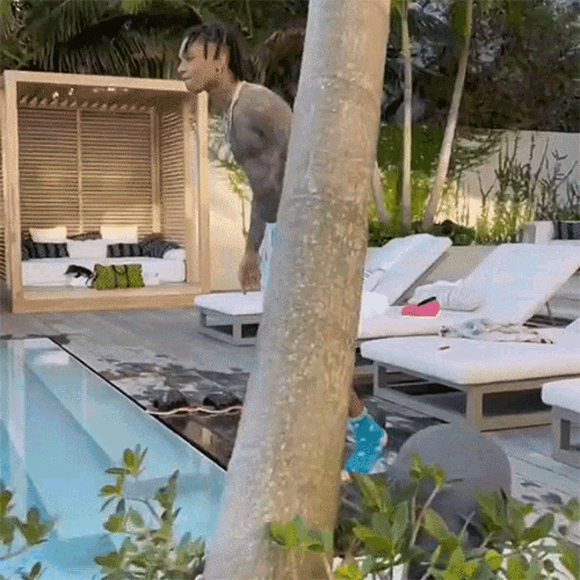 a man is standing in front of a swimming pool in a backyard