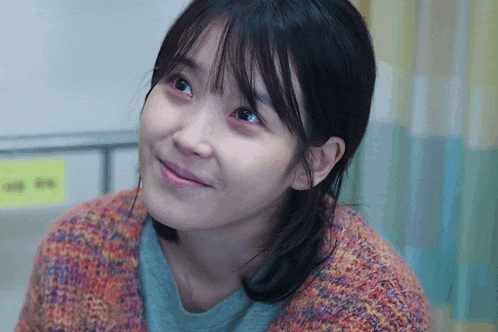 a close up of a woman 's face in front of a yellow sign that says ' ee ' on it