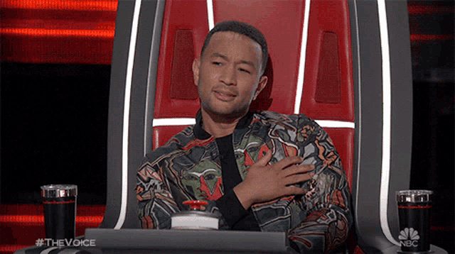 a man is sitting in a chair with his hand on his chest and the words #thevoice on the bottom left