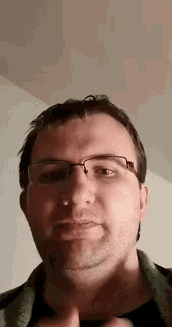 a man wearing glasses and a green sweater is making a face .