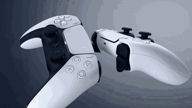 two white playstation controllers are laying on a dark background