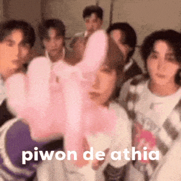 a group of young men are standing next to each other and holding a pink stuffed animal .