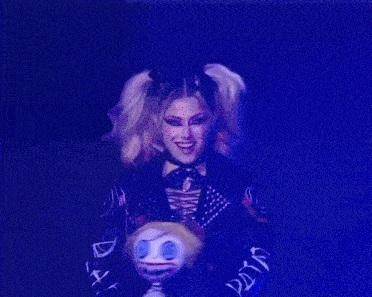a woman with pigtails is holding a doll and smiling