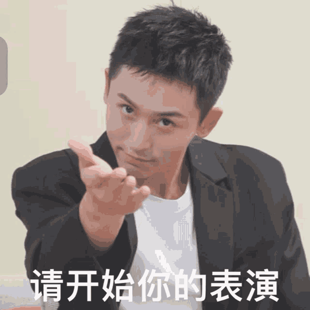 a man in a black jacket is pointing his finger at the camera with chinese writing below him
