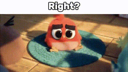 a red angry bird is sitting on a blue rug on a wooden table .