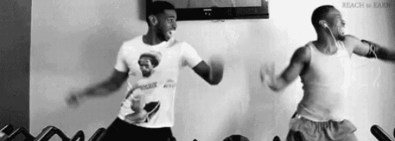 two men are dancing in a gym in front of a television .