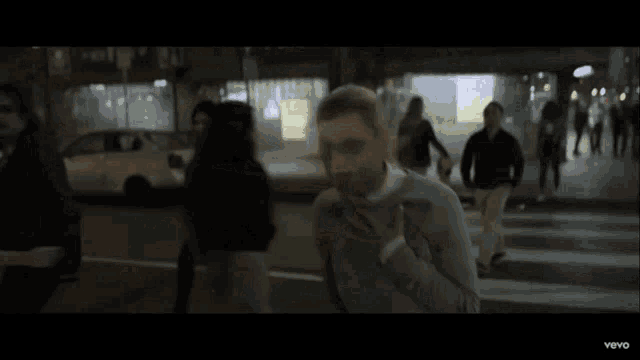 a man in a suit and tie is running down a street in a vevo video