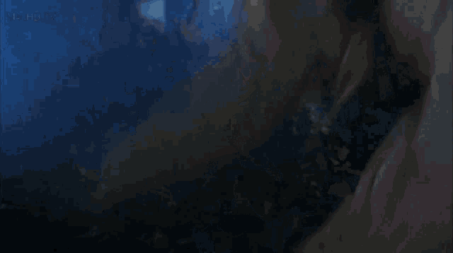 a man in a white shirt and tie is laying down in a dark room with a blue background that says netflix