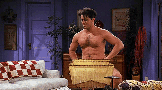 a man without a shirt is standing in a living room