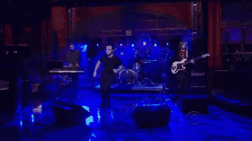 a man is playing a guitar on a stage with other people