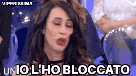 a woman is making a funny face with her eyes closed and the words unio l ho bloccato in front of her .