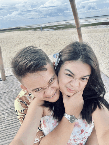 a man and woman are posing for a picture on the beach