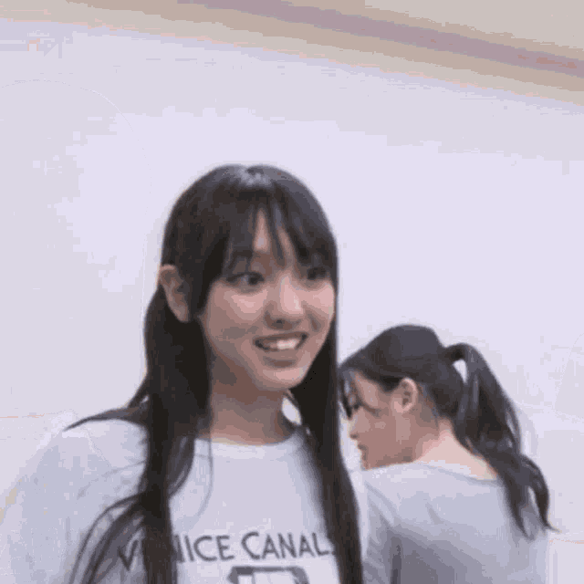two girls are standing next to each other and one of them is wearing a t-shirt that says `` nice canal '' .