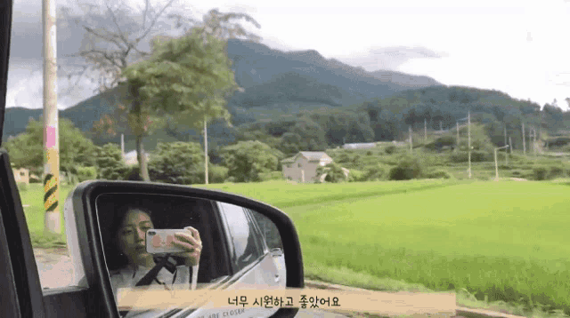 a woman taking a picture of herself in the rear view mirror