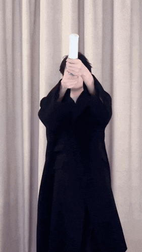 a man in a black coat is holding a white object