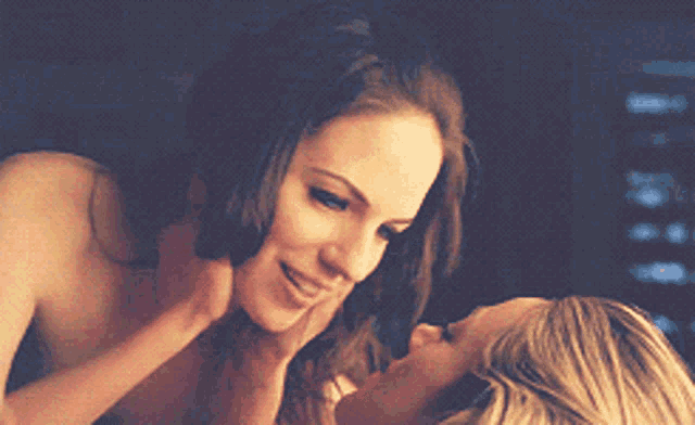 two women are kissing in a dark room and one is holding the other 's hand