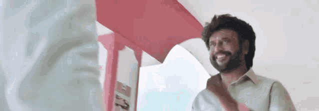a man with a beard is smiling while standing in front of a red door .