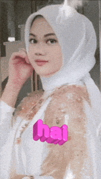 a woman wearing a white hijab with the word hai written in pink