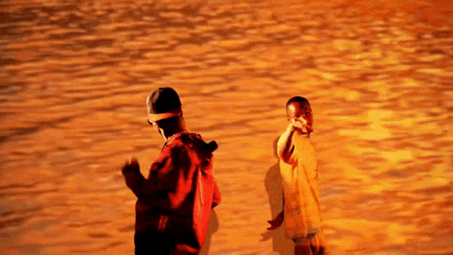 a man in a red hoodie is standing next to a boy in an orange shirt