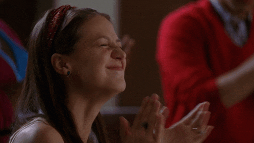 a girl is smiling and clapping her hands in a classroom