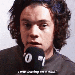 a man with curly hair is holding a microphone and says i was leaving on a train