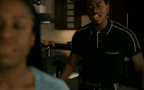 a man in a black shirt is standing next to a woman in a kitchen