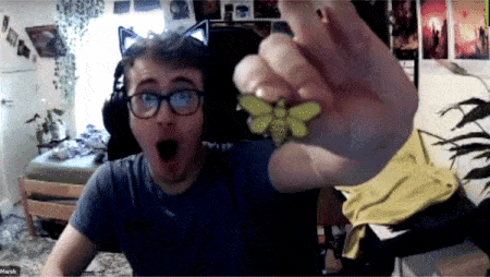 a man wearing glasses and headphones is holding a bee shaped pendant
