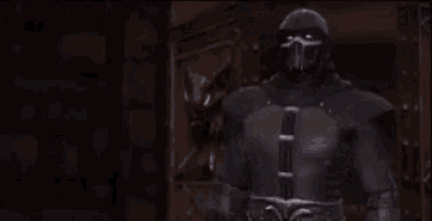 a man in a hooded costume is standing in a dark room .